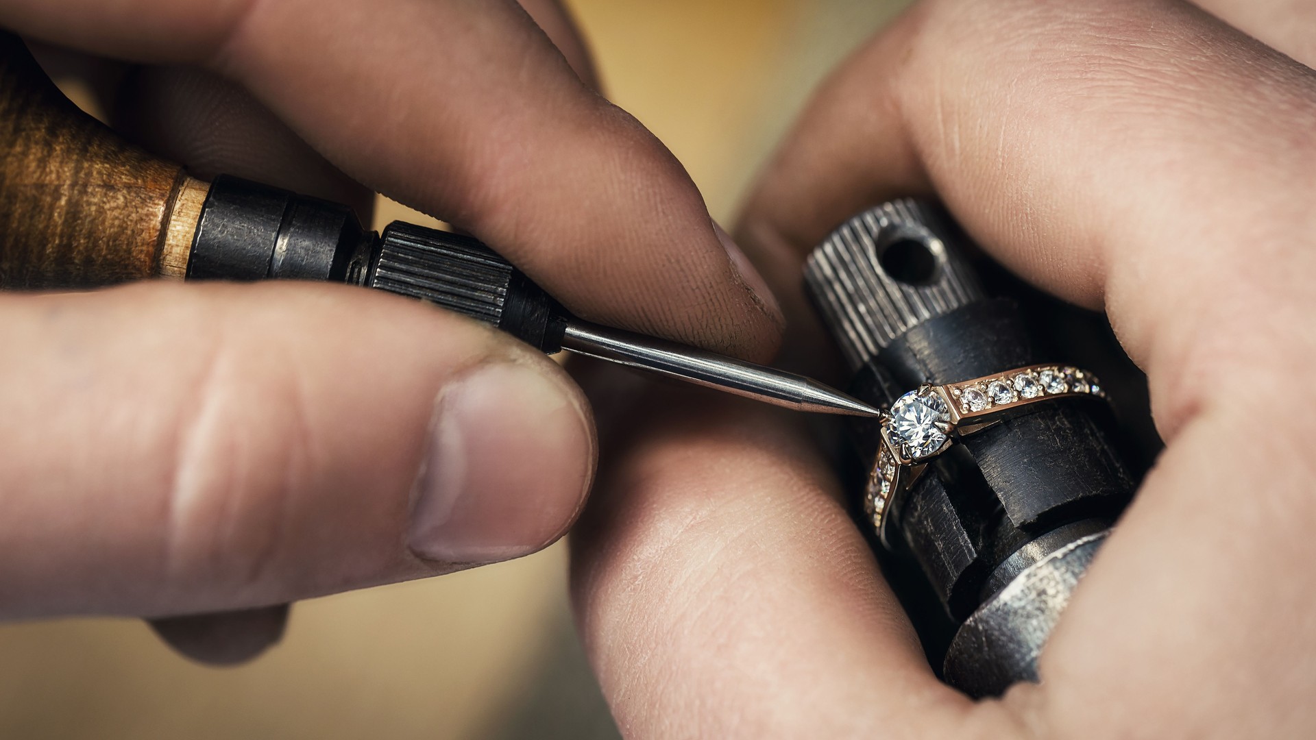Jeweler repairing a gold ring, adjusting the gems on the product, close-up